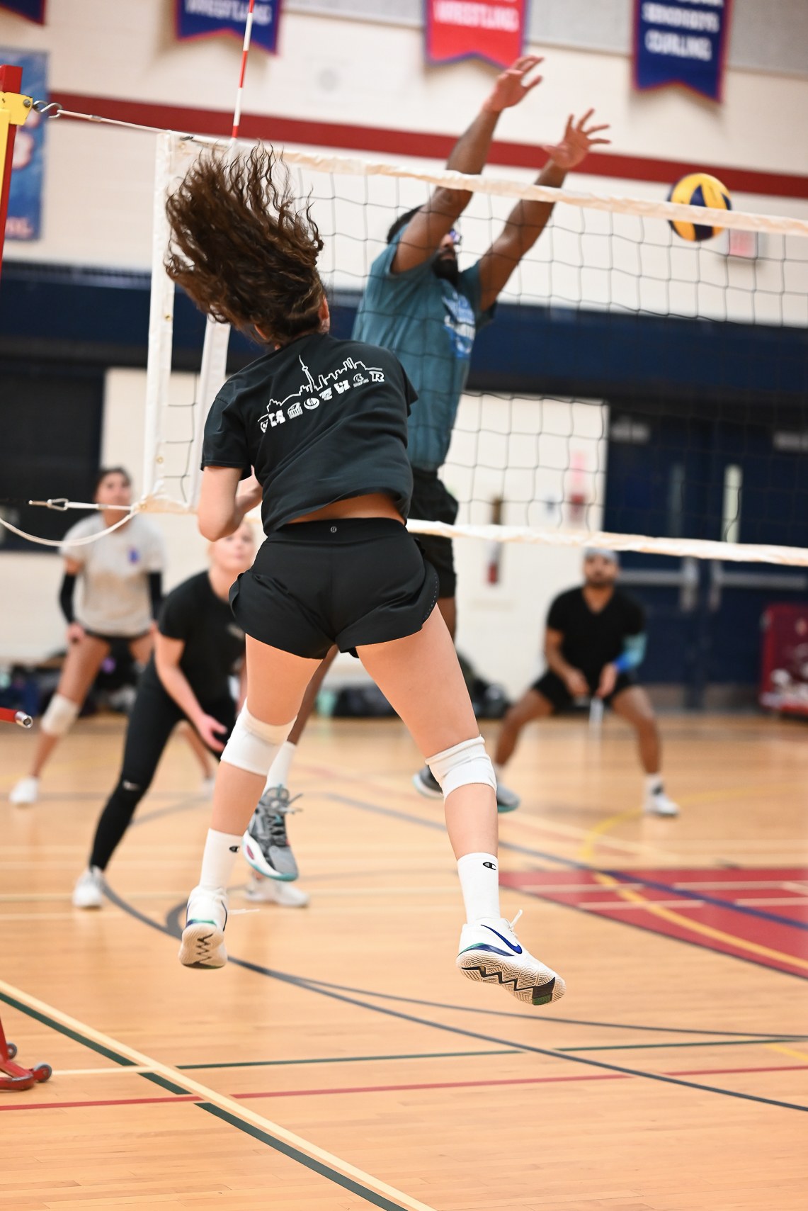 A volleyball player attacks at the net as an opponent blocks.
