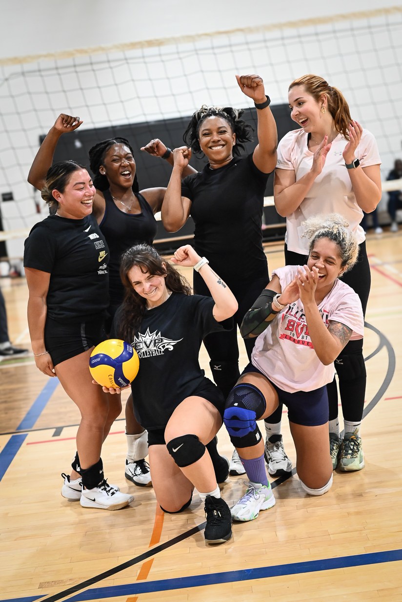 Volleyball teammates celebrating together on an indoor court.